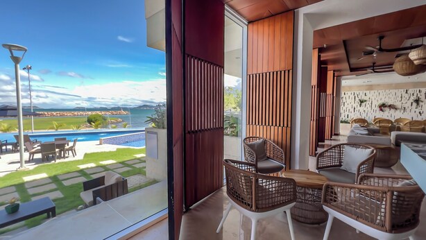 A modern living room with a view of a swimming pool and mountains.