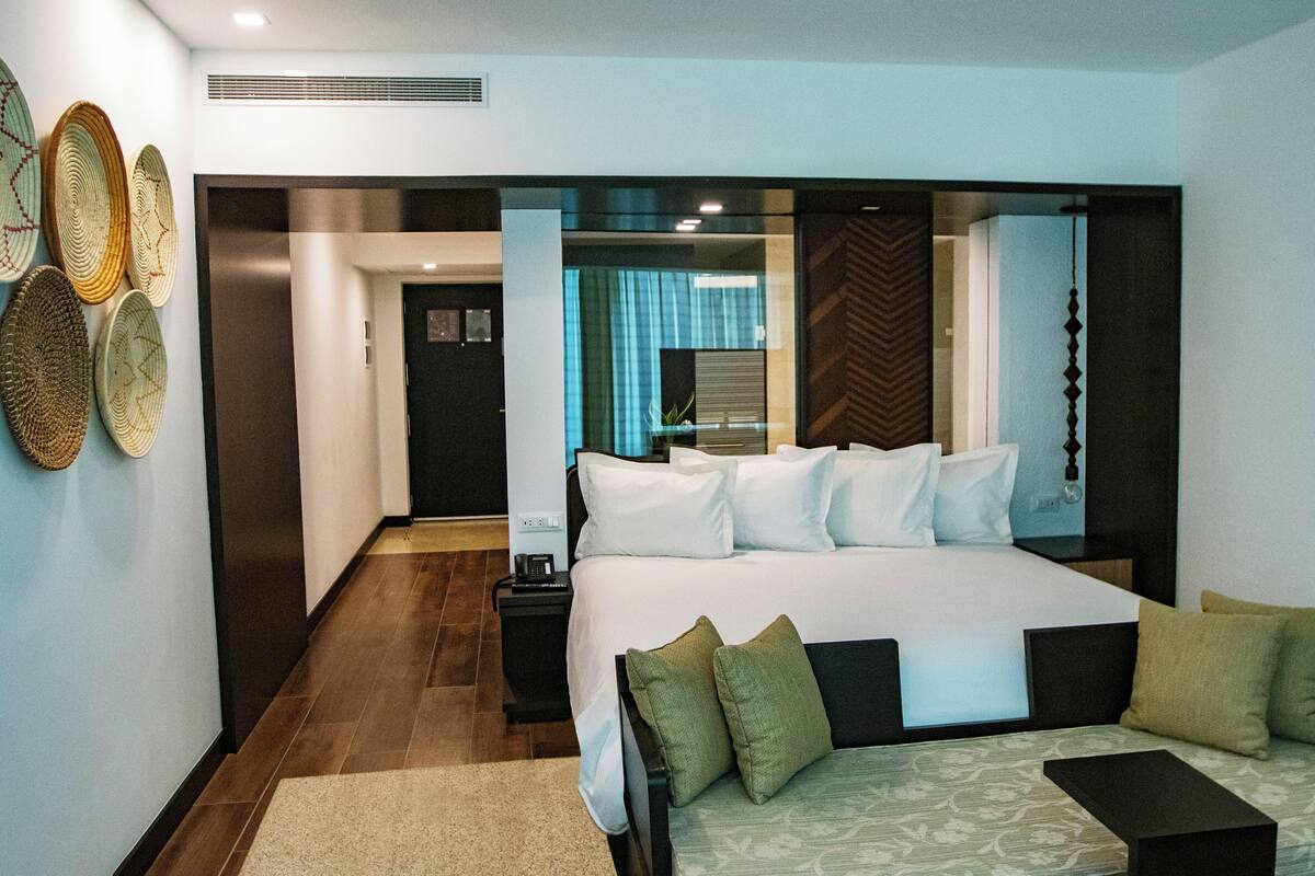 Una habitación de hotel moderna con una cama grande, una mesita de noche y un televisor montado en la pared.