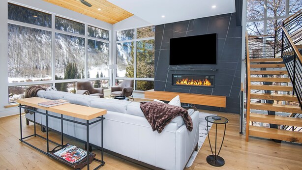 Ein modernes Wohnzimmer mit großem Fenster, Kamin, Sofa und Treppe.