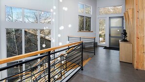 Ein modernes Interieur mit einer Treppe, großen Fenstern und einer Wand mit Holzverkleidung.
