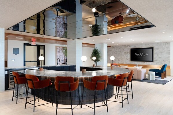 A modern kitchen with a central island, bar stools, and a flat-screen TV on the wall.