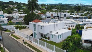 A modern residential building with a flat roof, solar panels, and a white fence. - Charming 4-bedroom Estate with In-ground pool WiFi in San Juan (Guaynabo)