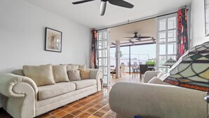 A living room with a beige sofa, a patterned armchair, and a tiled floor. - Charming 4-bedroom Estate with In-ground pool WiFi in San Juan (Guaynabo)