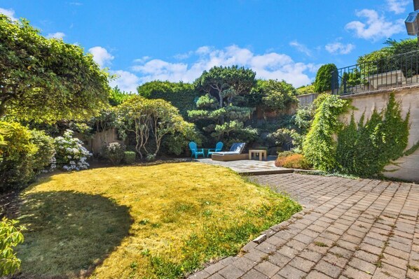 Ein Garten mit Rasenfläche, Terrasse und Sitzbereich.