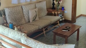 Una sala de estar con un sofá, una mesa de centro, una lámpara y un cuadro en la pared.