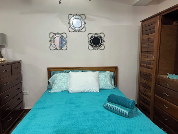 A bedroom with a bed, a dresser, and a wardrobe.