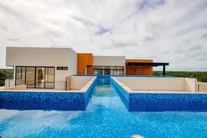 A modern hotel with a swimming pool, large windows, and a view of the surrounding landscape. - Giada Towers by The Spot Rentals (Tulum)