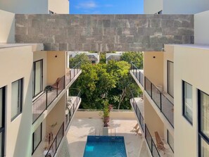 A modern building with a pool, balconies, and a view of greenery. - Giada Towers by The Spot Rentals (Tulum)