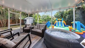A covered outdoor area with a hot tub, wicker furniture, and a children's play structure. - Cozy 4/3, Patio, King Bed, Bunk Room + Water Park! (Sanford)