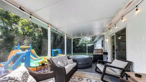 A covered patio with wicker furniture, a slide, and a hot tub. - Cozy 4/3, Patio, King Bed, Bunk Room + Water Park! (Sanford)