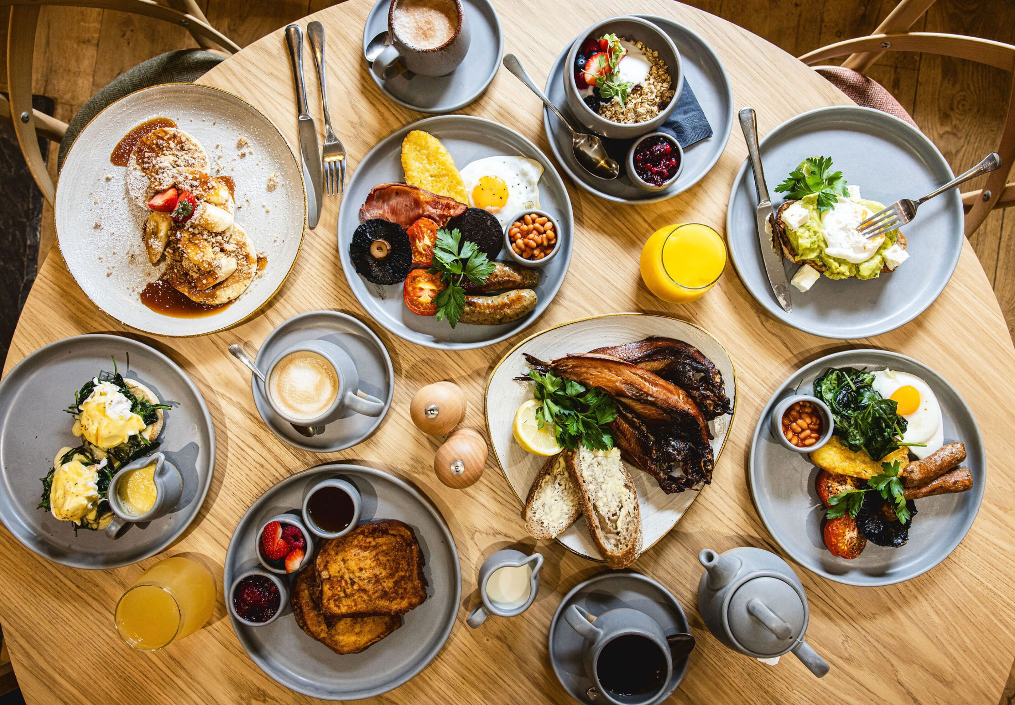 A round table with various breakfast dishes, including eggs, bacon, toast, and fruit.