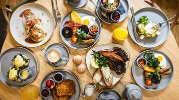 A round table with various breakfast dishes, including eggs, bacon, toast, and fruit.