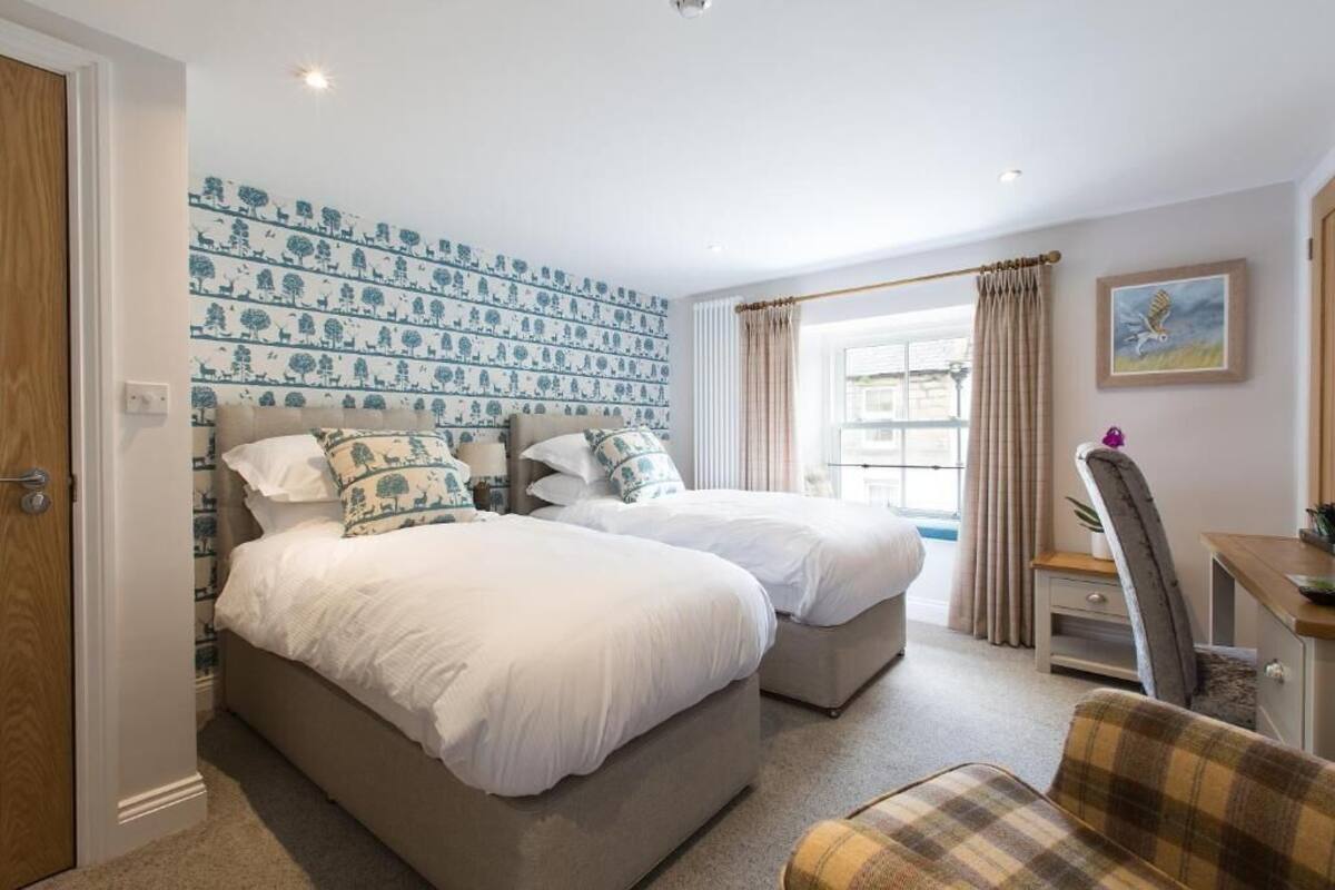 A bedroom with two beds, a desk, and a chair.