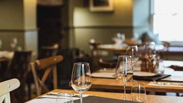 A restaurant interior with wooden tables, chairs, and wine glasses.