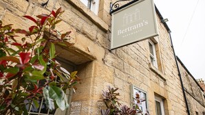 A sign for 'Bertram's Warkworth' on a stone building.