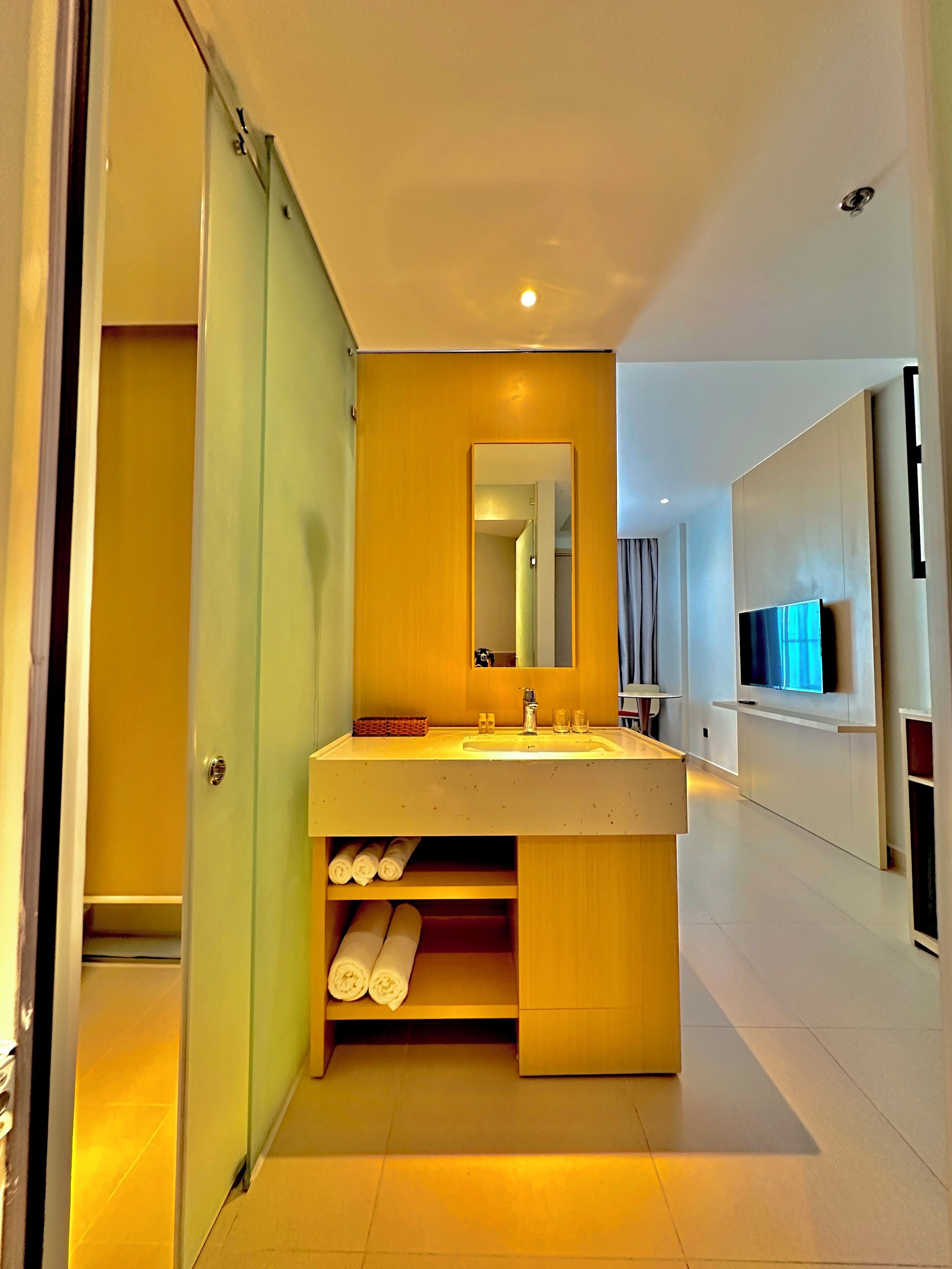 Een moderne badkamer met een wastafel, spiegel en ingebouwde planken.