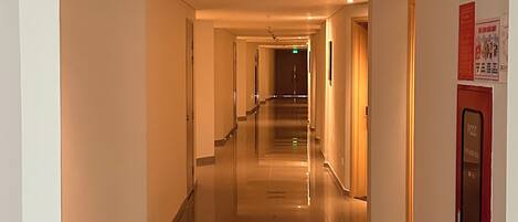 A long, well-lit hallway with a polished floor, leading to a staircase.