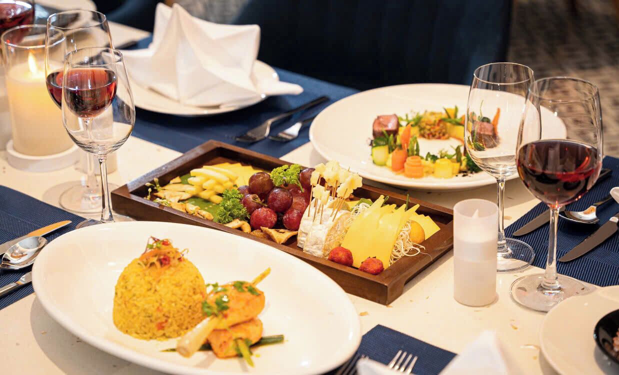 A dining table set with plates of food, glasses of wine, and candles.
