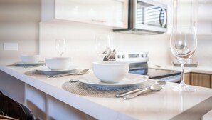 A modern kitchen with white cabinetry, a central island with a bowl and wine glass, and a microwave above the stove.