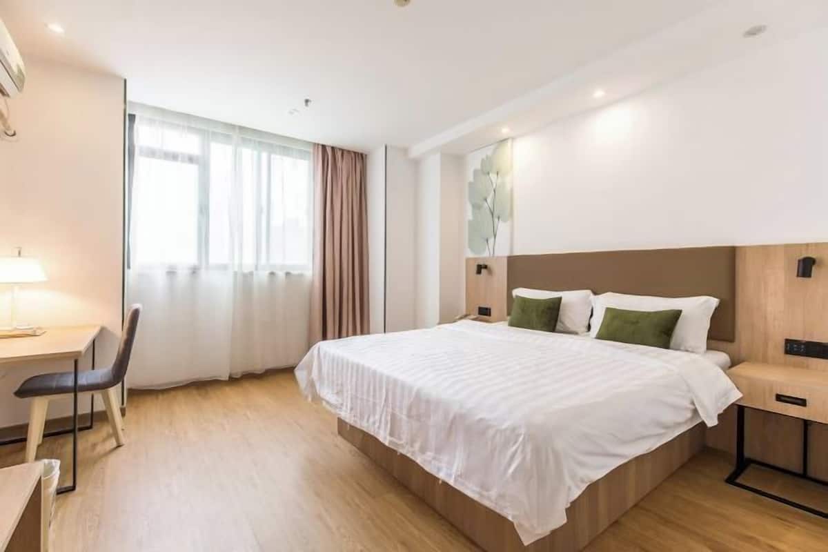 A hotel room with a bed, a desk, a chair, and a window with curtains.