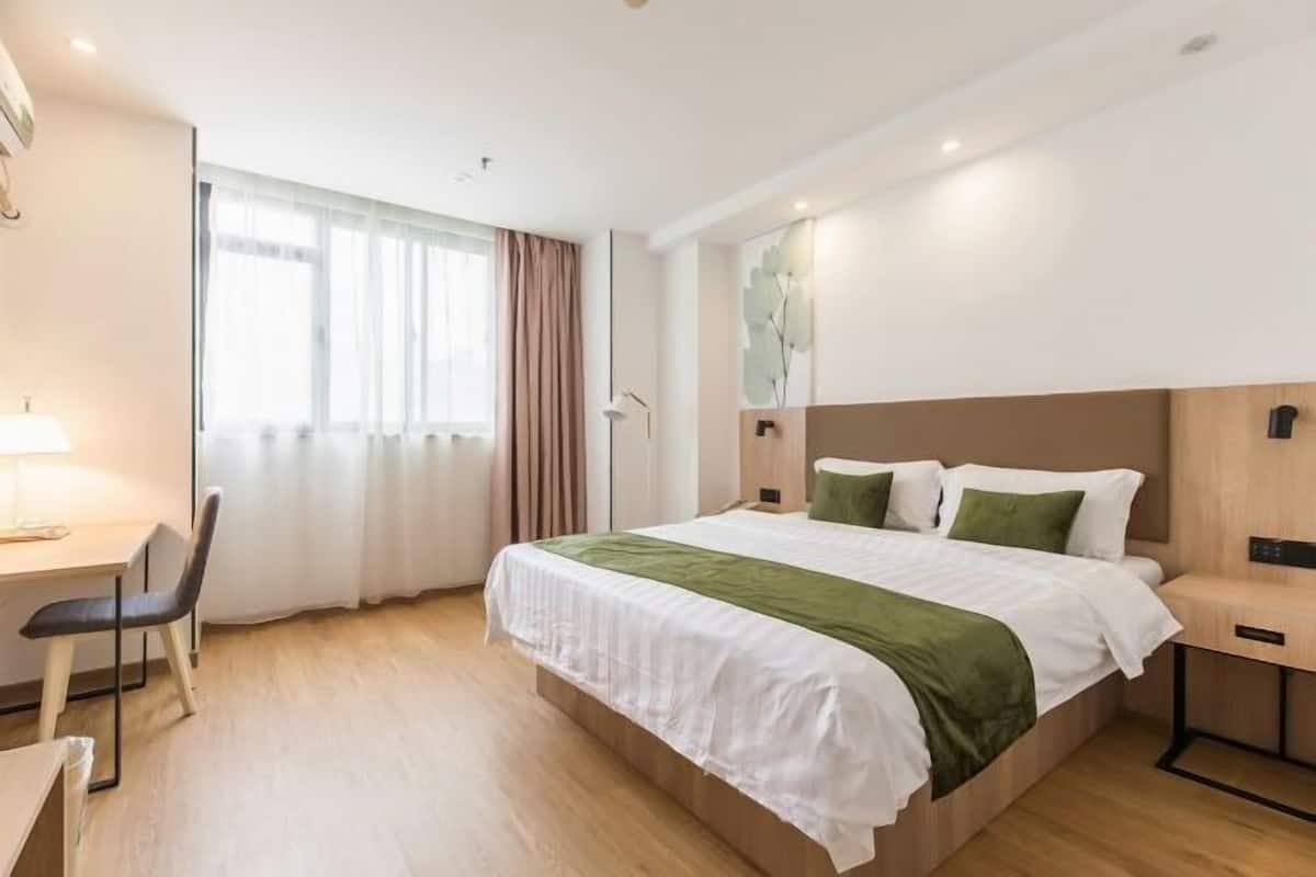 A modern hotel room with a bed, desk, chair, and a window with curtains.