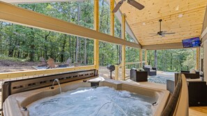 A hot tub in a wooden cabin with a view of a forest.