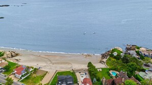 A coastal residential area with a beach, houses, and a clear view of the sea.