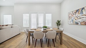 A modern dining area with a wooden table, six chairs, and a central plant. - Luxury Group Retreat | Rooftop Deck + Chef's Kitchen | Sleeps 10 (Houston)