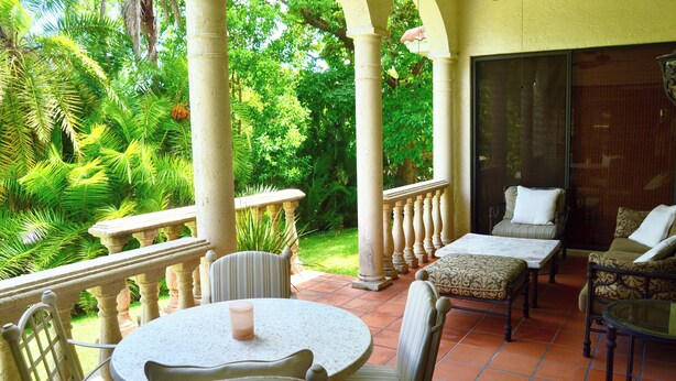 Un patio couvert avec une table ronde et des chaises, un canapé et une table en verre.