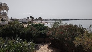 A pathway leading to a waterfront with a view of the sea and buildings in the background.