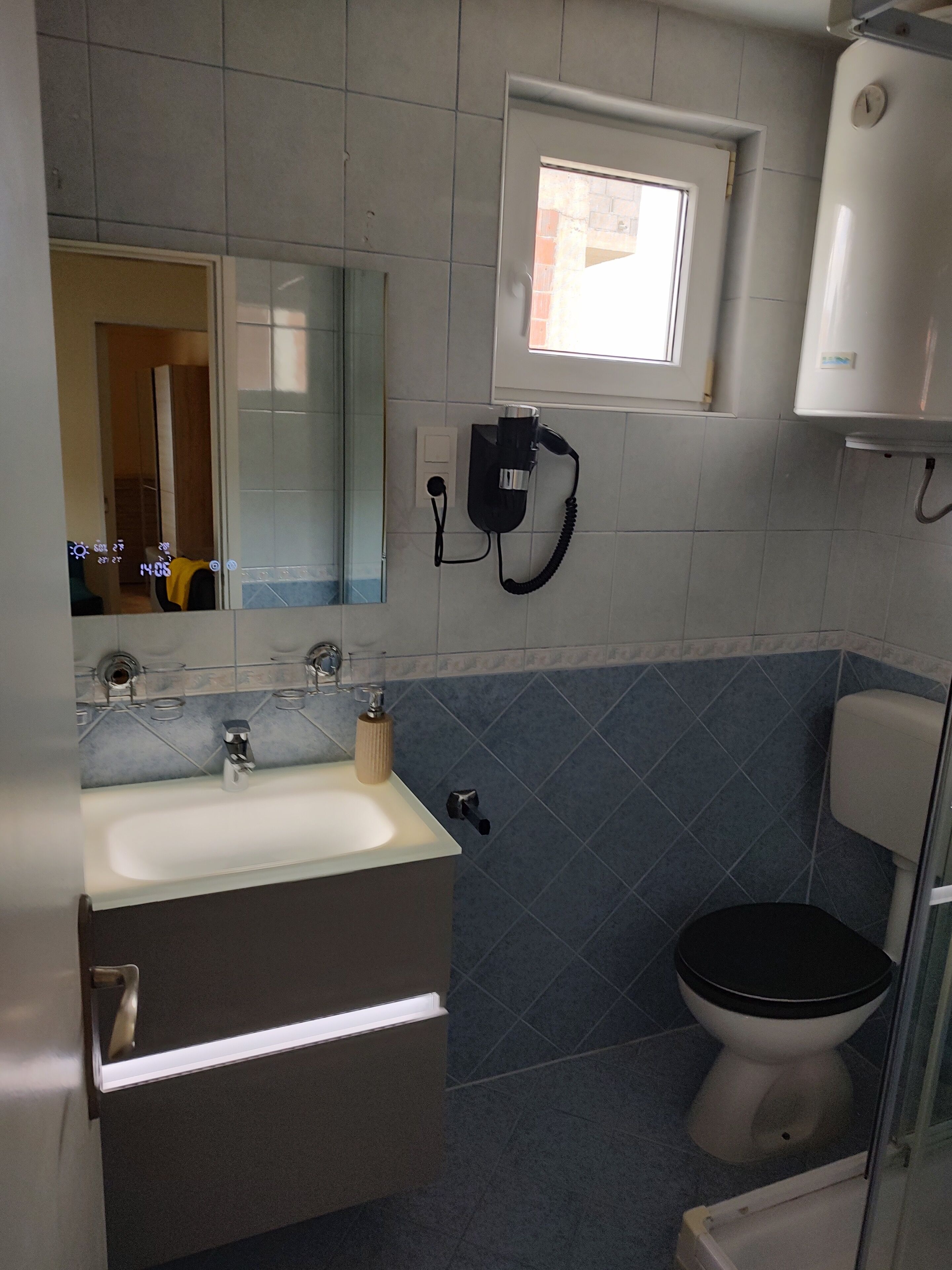 Ein Badezimmer mit Waschbecken, Spiegel, Toilette und Fenster.