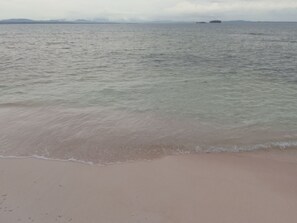Una spiaggia con acque limpide e un'isola all'orizzonte.