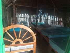 Una habitación con dos camas de madera, una silla de madera y una pared de bambú.