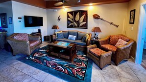 Un salon comprenant un canapé, deux fauteuils, une table basse, un téléviseur et un ventilateur de plafond.