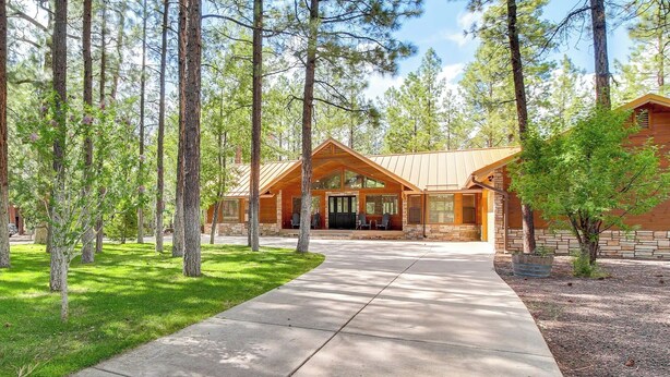A lodge with a covered front porch, stone walls, and a concrete driveway.