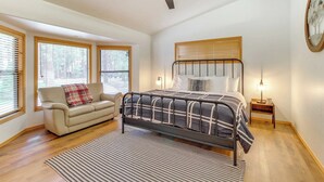 A bedroom with a bed, a chair, a ceiling fan, and a window.