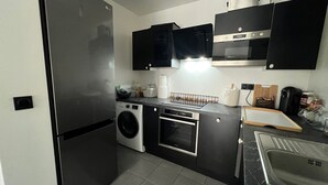 Cocina compacta equipada con refrigerador, lavadora, horno y microondas.