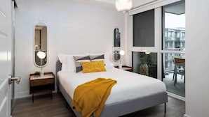 A modern bedroom with a large bed, bedside tables, a mirror, and a view through a large window. - Amazing 2BR/2BA Resort Condo w/ Balcony & Parking! (Innisfil)