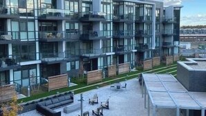 A modern multi-story building with balconies, outdoor seating, and a covered patio area. - Amazing 2BR/2BA Resort Condo w/ Balcony & Parking! (Innisfil)
