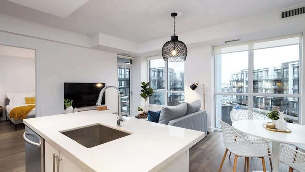 A modern kitchen with a large island, white cabinetry, and a black pendant light. - Amazing 2BR/2BA Resort Condo w/ Balcony & Parking! (Innisfil)