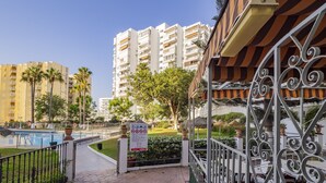Zona turística con piscina, espacio de estar cubierto al aire libre y vistas de edificios altos.