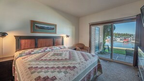 A bedroom with a large bed, a view of a marina through the sliding glass door, and a framed picture on the wall. - Lakefront - 3 Bedroom (Hope)
