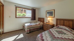A bedroom with two beds, a window with curtains, a bedside table with a lamp, and a framed picture on the wall. - Lakefront - 3 Bedroom (Hope)