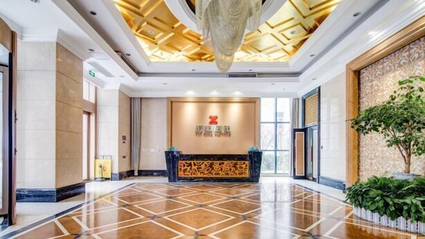 Un vestíbulo de hotel con piso de mármol pulido, un mostrador de recepción y una gran lámpara de araña.