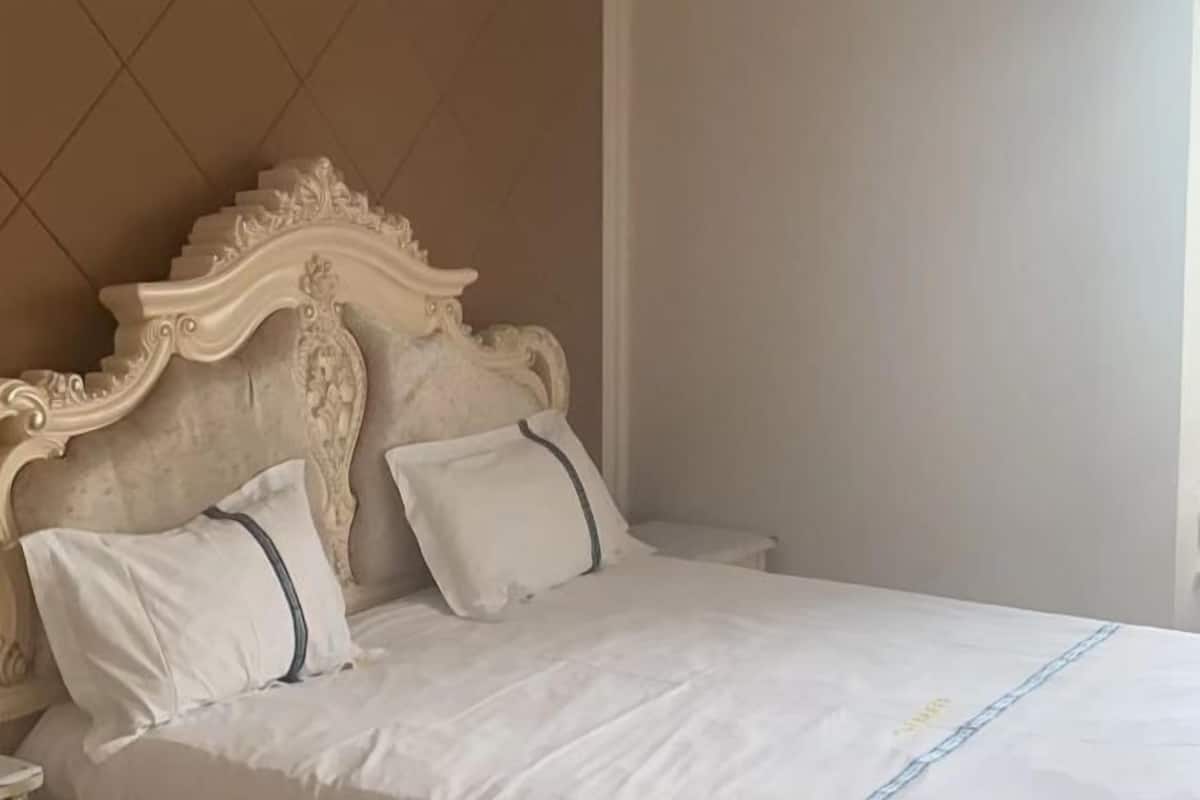 Ein Bett mit einem verzierten Kopfteil, weißer Bettwäsche und einem Nachttisch.