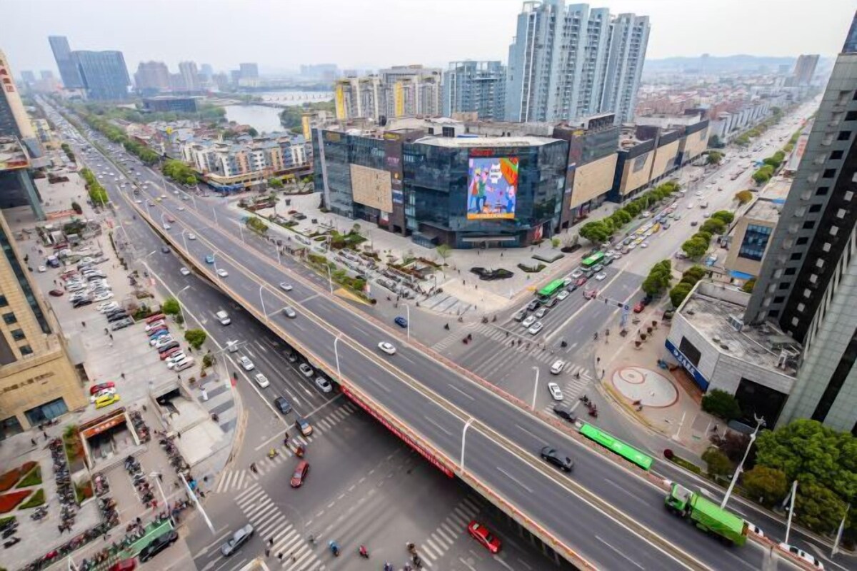 A multi-level urban street with a prominent building featuring a large billboard.