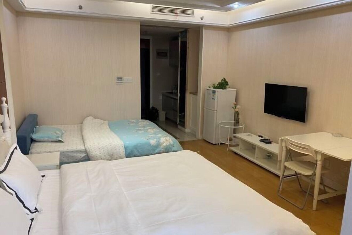 A hotel room with two beds, a TV, a desk, and a wardrobe.