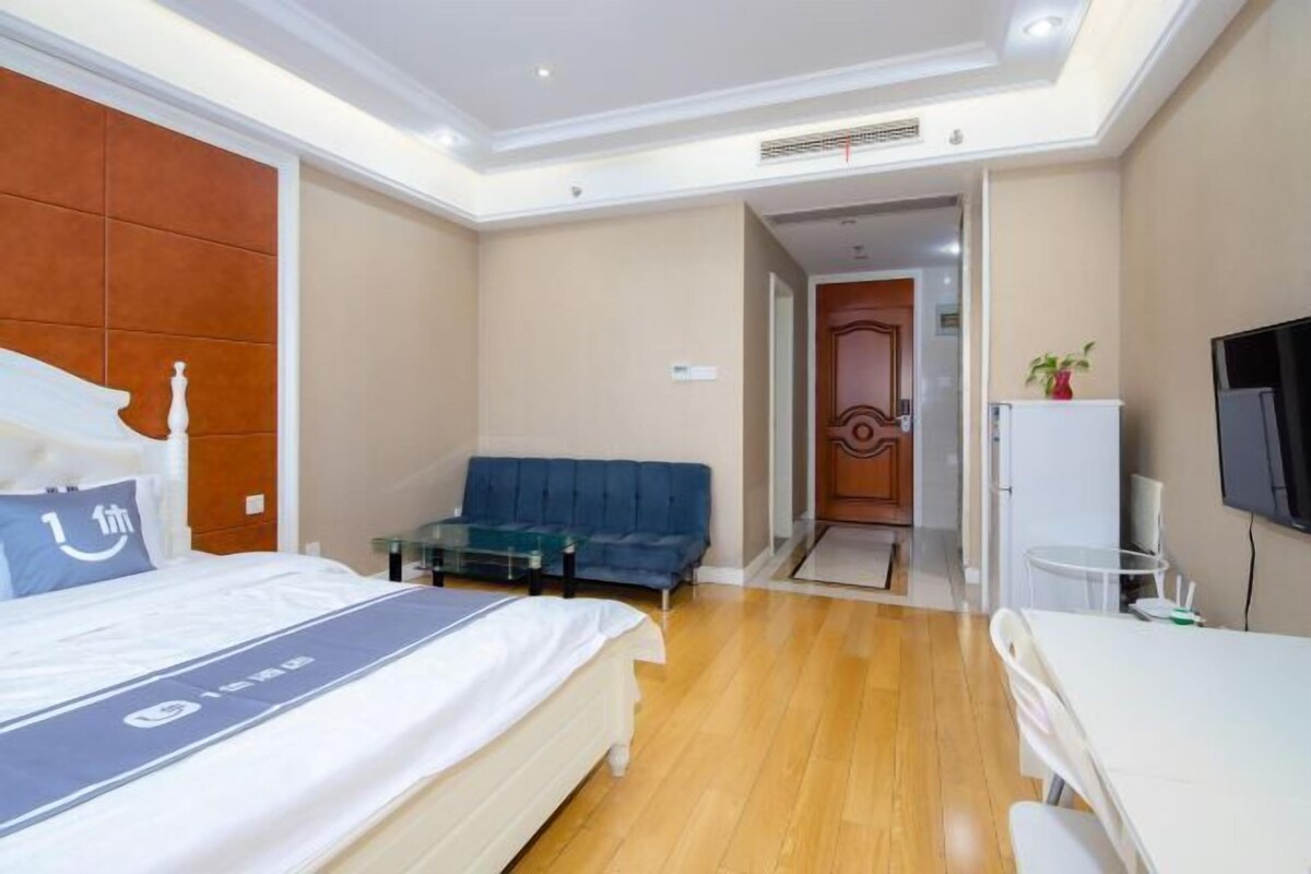 A hotel room with a bed, a sofa, a desk, and a television.