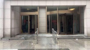 Entrada de hotel con diseño moderno, que presenta una puerta de vidrio y una barandilla de metal.