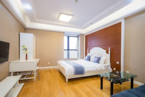 A bedroom with a bed, bedside table, a glass coffee table, a TV on the wall, and a window with a view. - Kaiweina Hotel (Shengtai Road Subway Station Store) (Nanjing)
